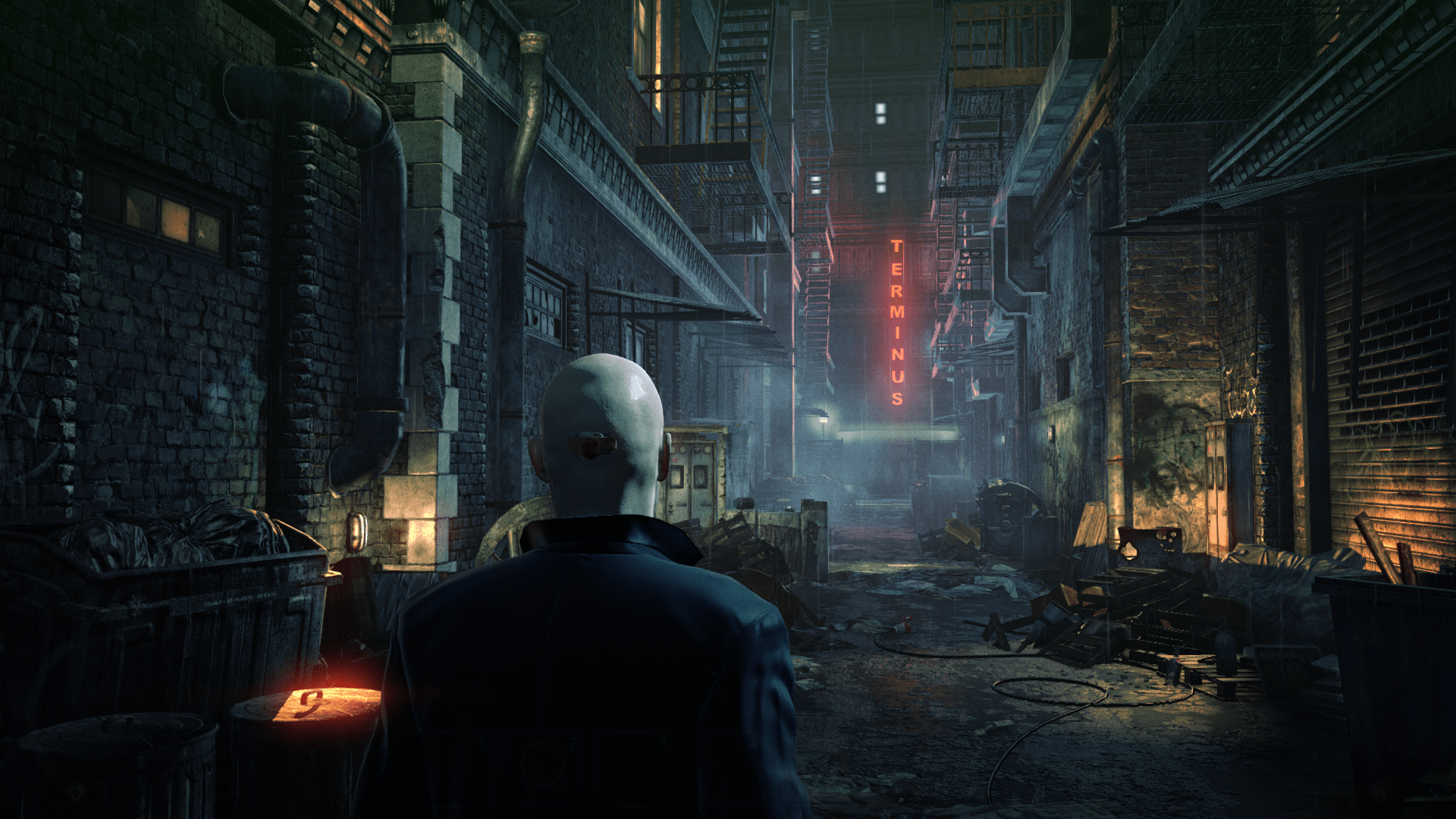 An image of Agent 47, seen from behind, standing in a cluttered alleyway in the rain.  In the distance, a glowing neon sign says "Terminus".
